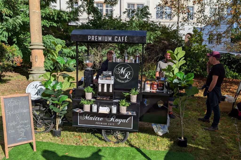 Schwarzes Kaffeerad von Maitre Royal unter Bäumen im Schlossgarten bei einer Veranstaltung im Freien