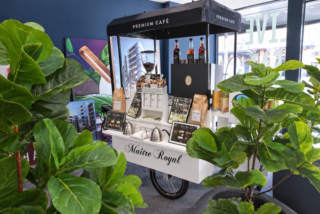 Weißes Kaffeerad von Maitre Royal in der Lobby eines Bürogebäudes zwischen großen Zimmerpflanzen