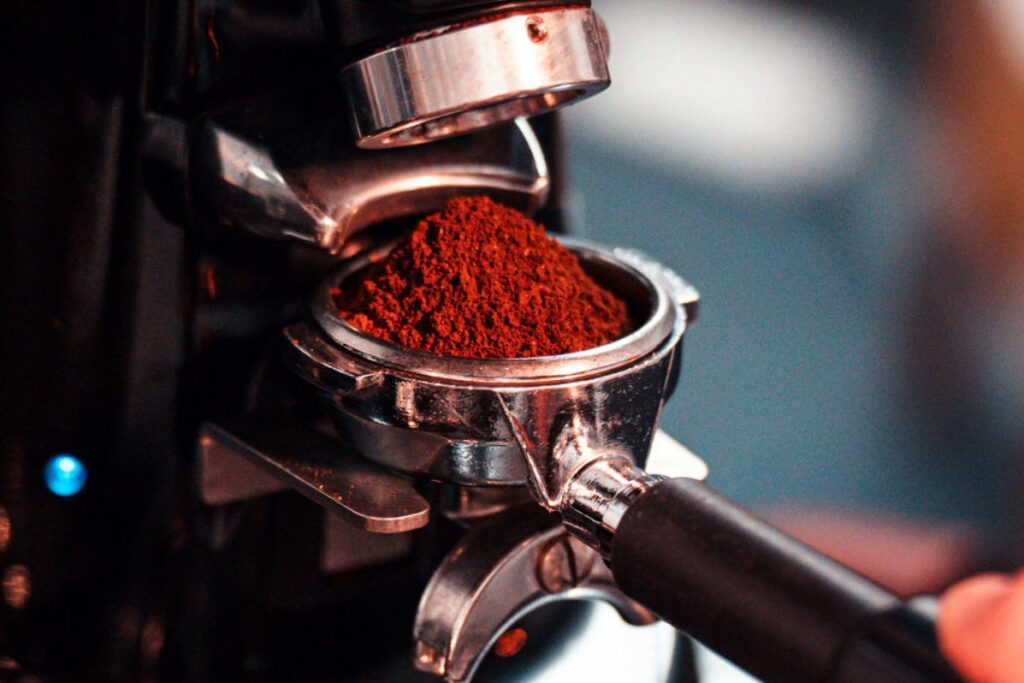 Siebträger mit frisch gemahlenem Kaffeepulver unter dem Auslauf der Kaffeemühle