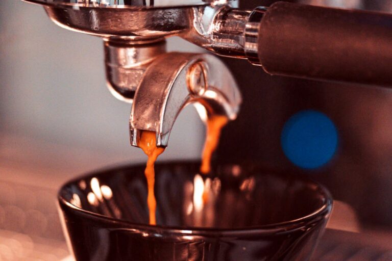 Espresso läuft aus dem Siebträger in eine Tasse, Nahaufnahme mit warmem Licht